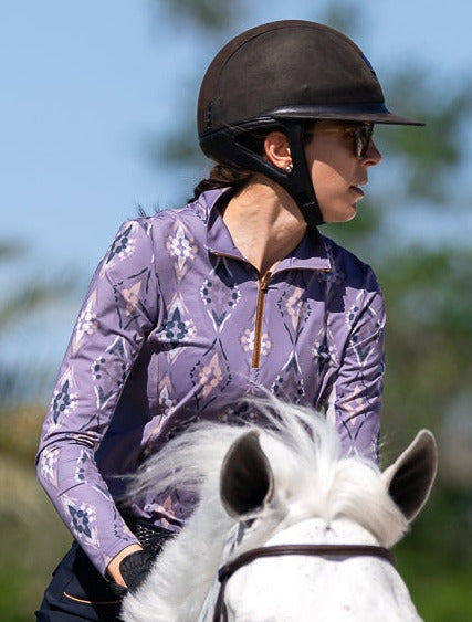 Person riding a white horse in an outdoor setting with greenery