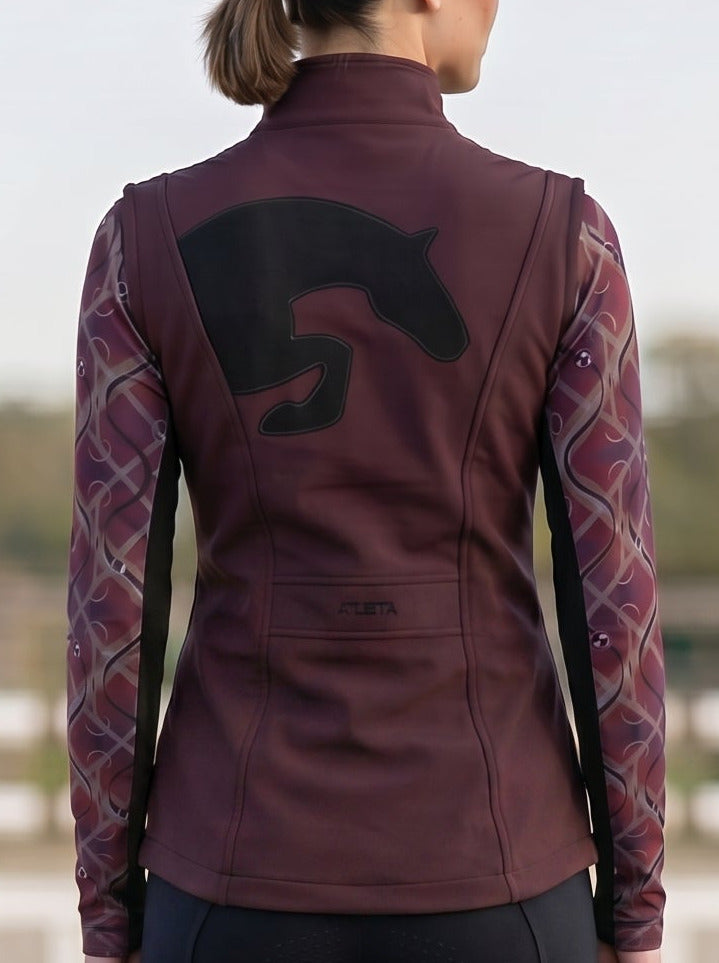 Person wearing equestrian attire with a maroon jacket and black leggings in an outdoor setting.
