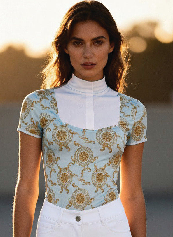 Woman wearing a patterned top and white pants standing outdoors with a blurred background