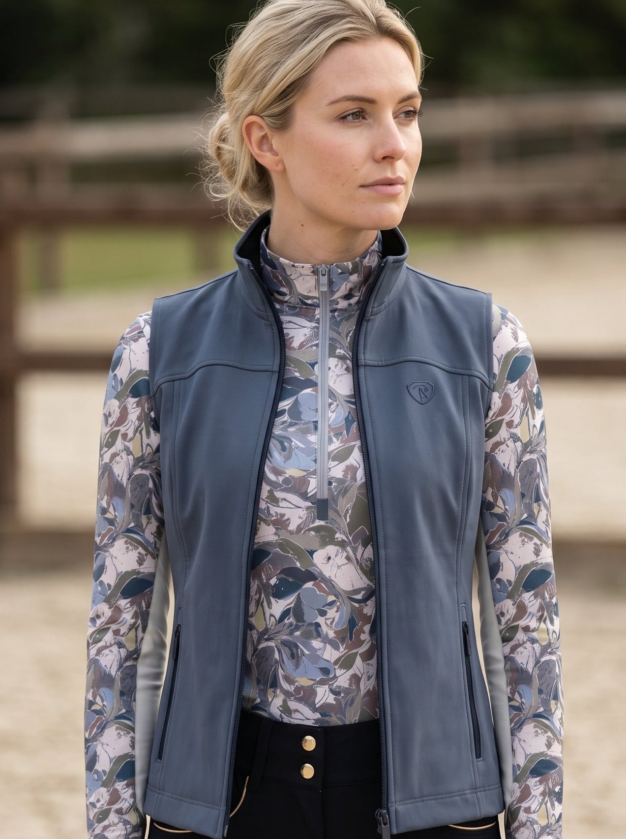 Woman wearing a patterned shirt and blue vest outdoors