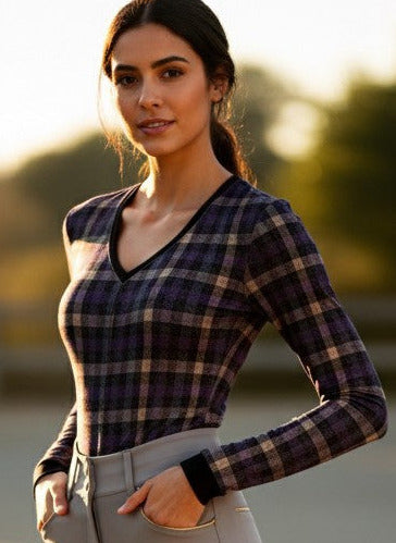 Woman in equestrian attire standing on a dirt arena with sunset lighting