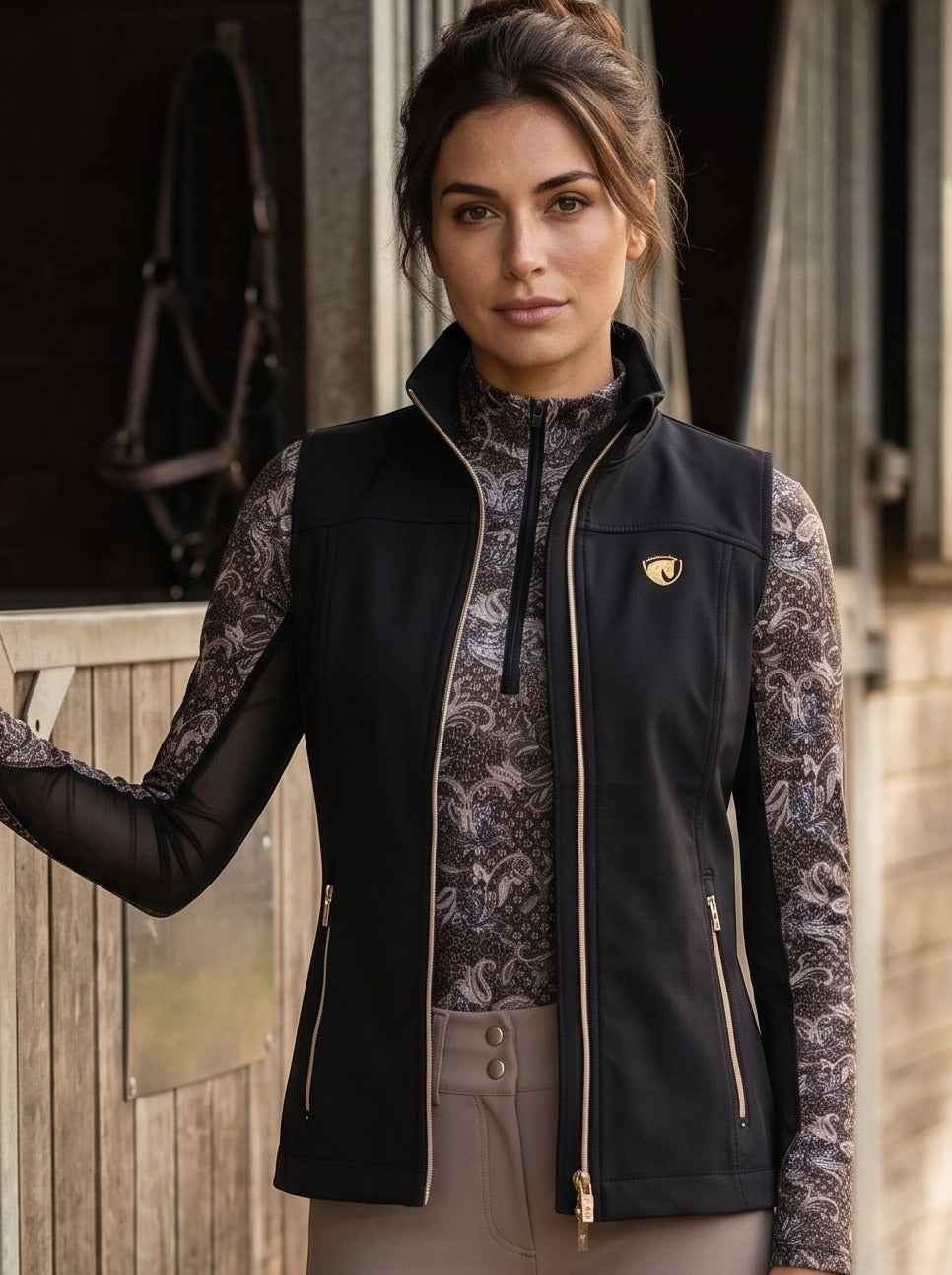 Woman in equestrian attire standing next to a wooden stable door.