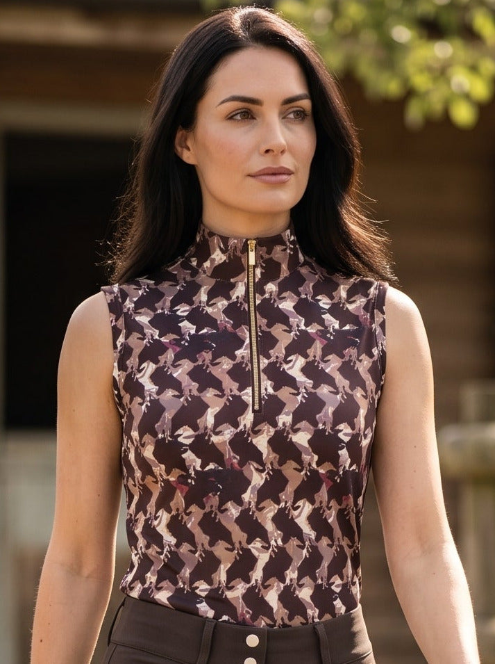 Woman in equestrian attire walking outdoors near a wooden stable.