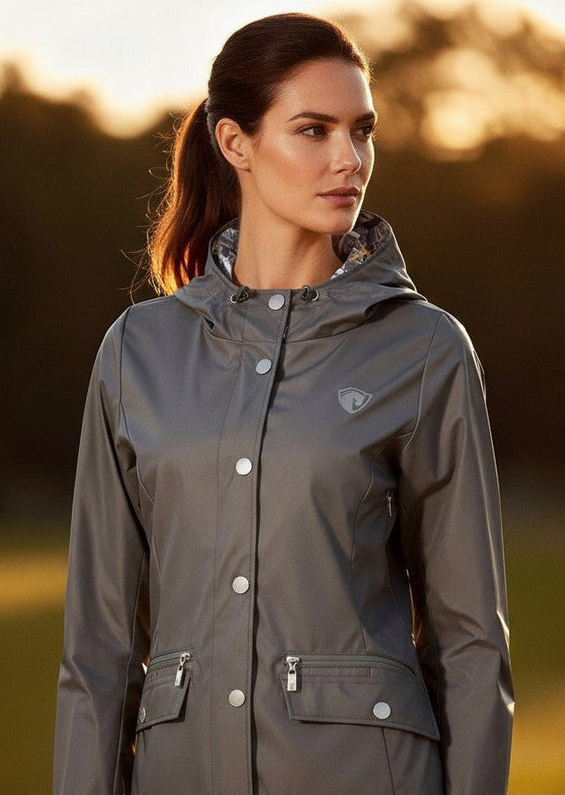 Woman wearing a gray raincoat standing in a field with a blurred background