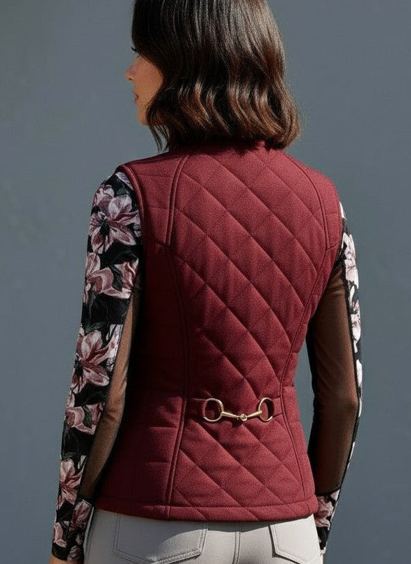 Person wearing a maroon quilted vest with floral sleeves against a gray background