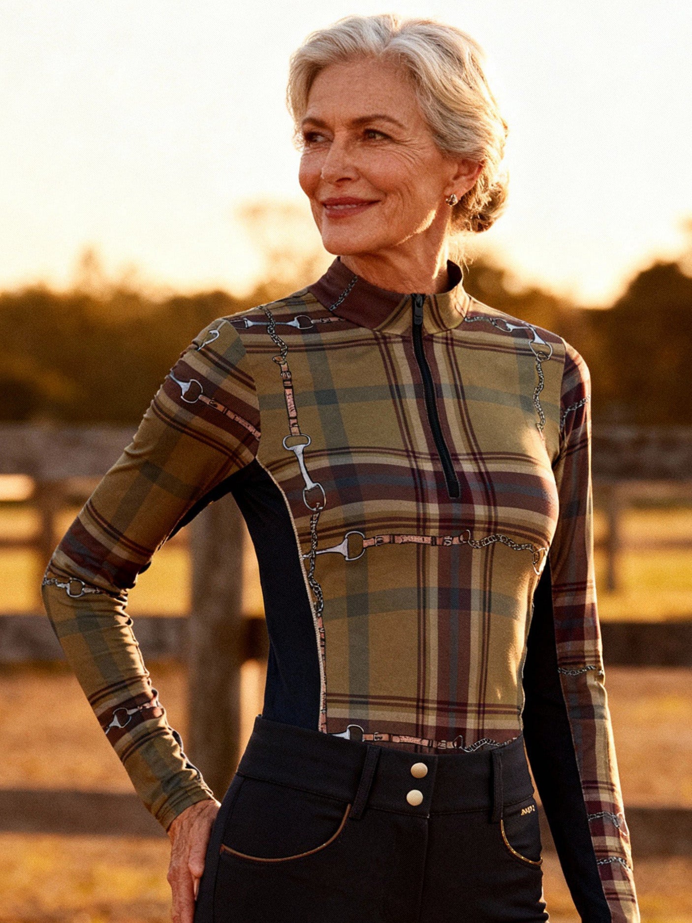 Woman in equestrian attire standing next to a horse in a field at sunset.